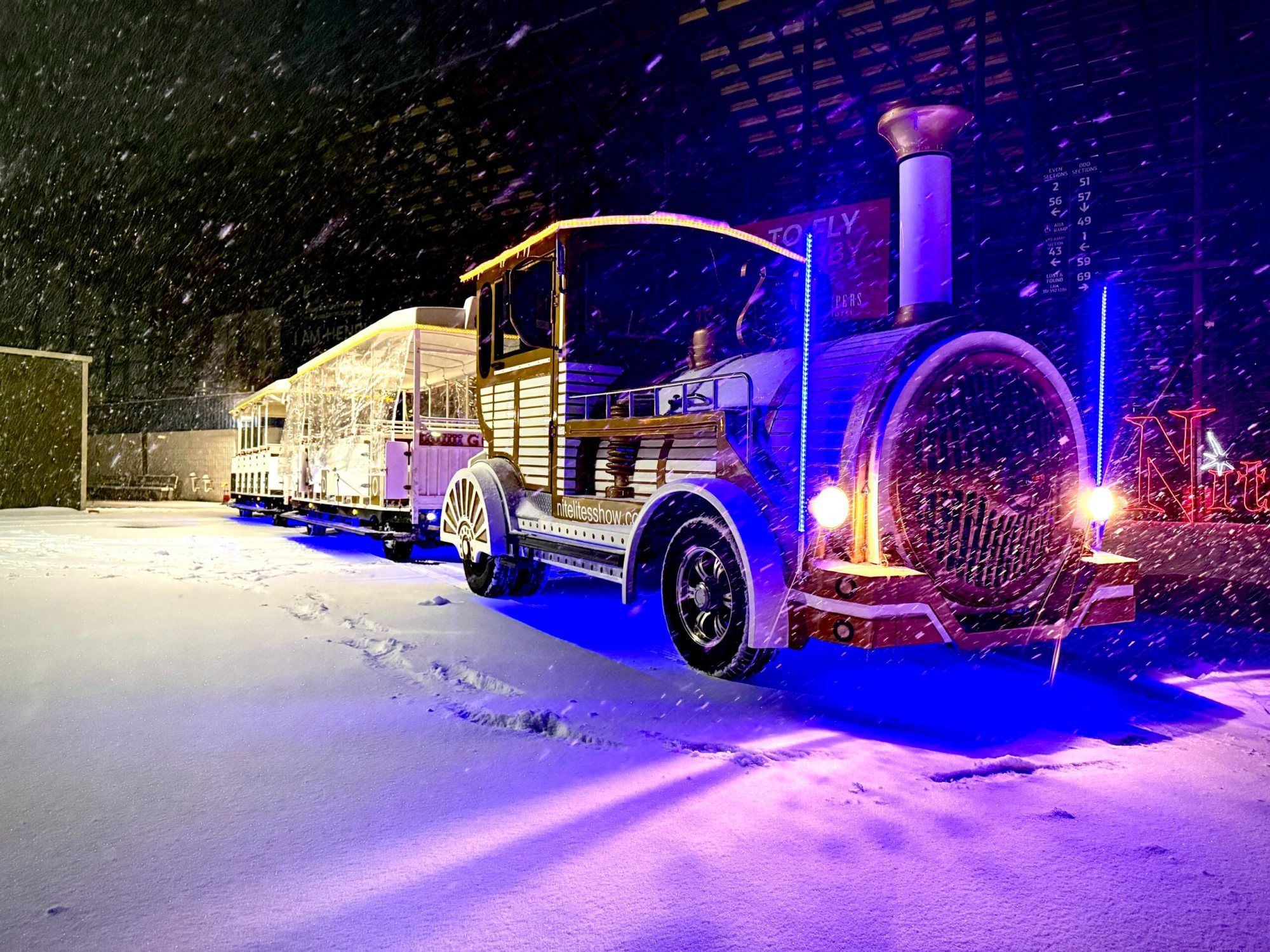 The Nite Lites train passing Christmas light displays in the snow