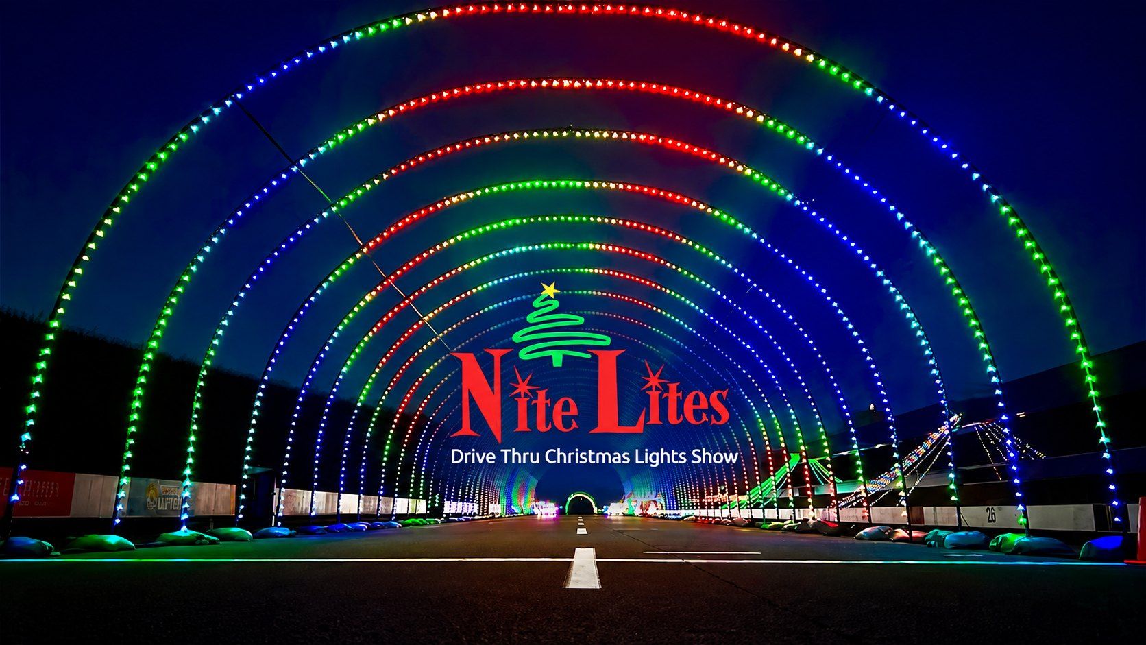 A tunnel of Christmas lights arching over the drive-thru route at night