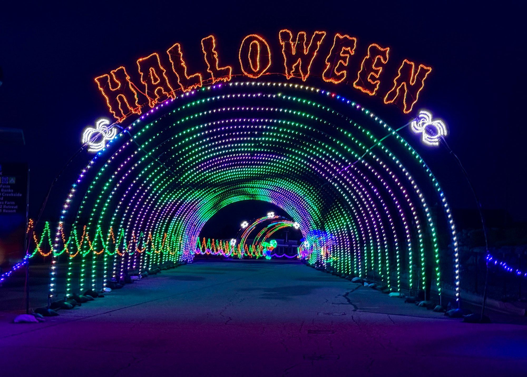 Cars driving through a glowing orange Halloween light tunnel at the Nite Lites show