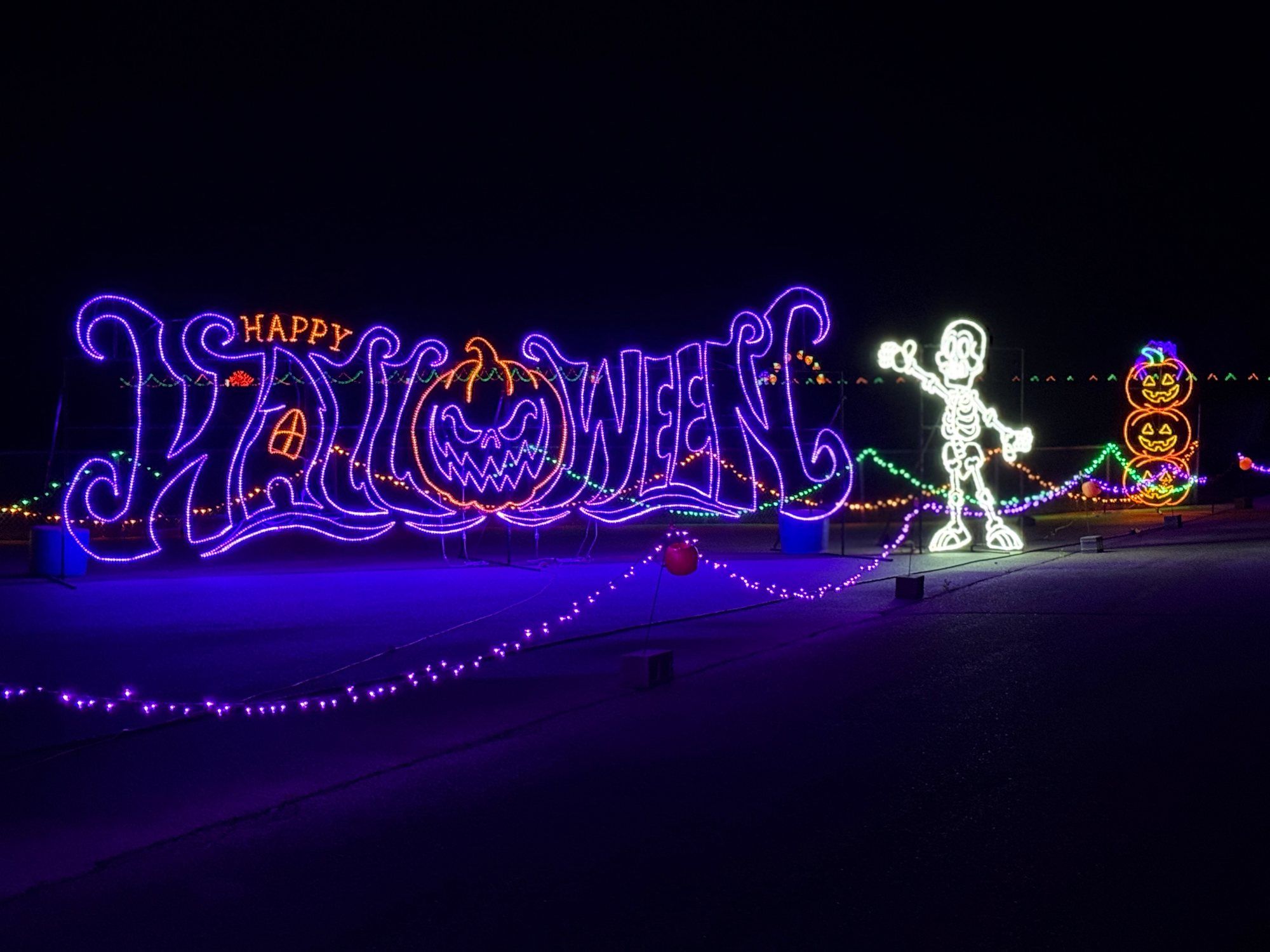Skeleton beside a glowing Happy Halloween sign