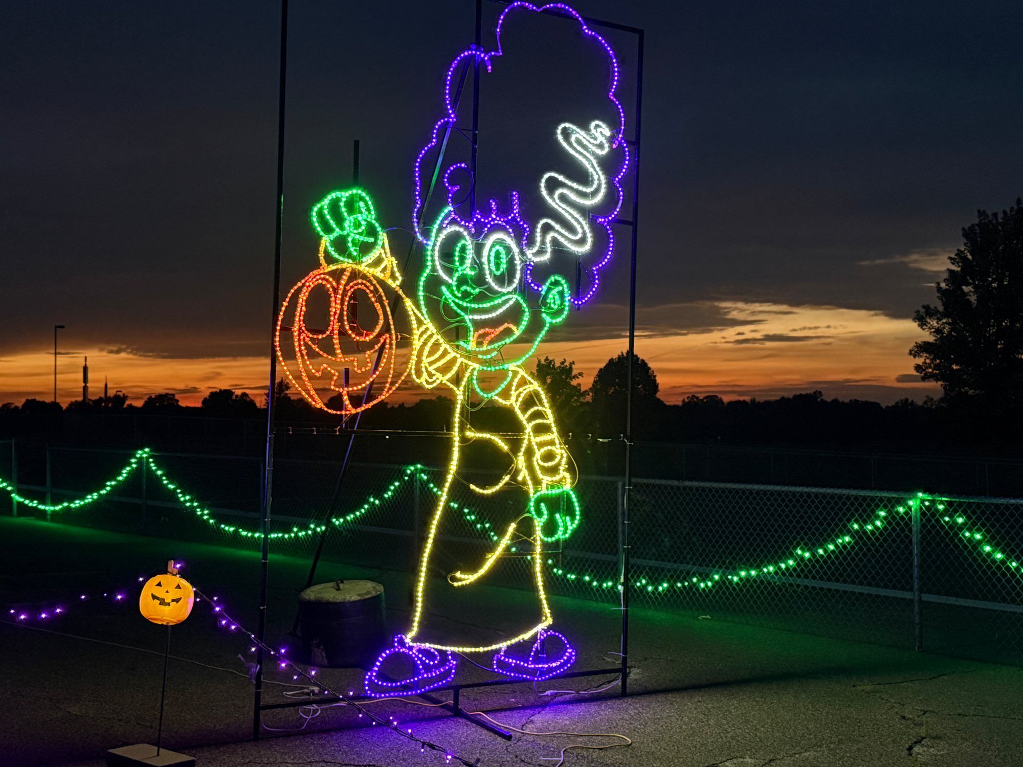 Witch and jack-o’-lantern light display glowing at night